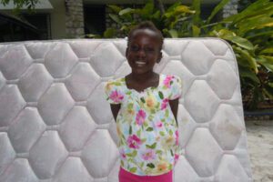 A picture of the girl standing near the white bed