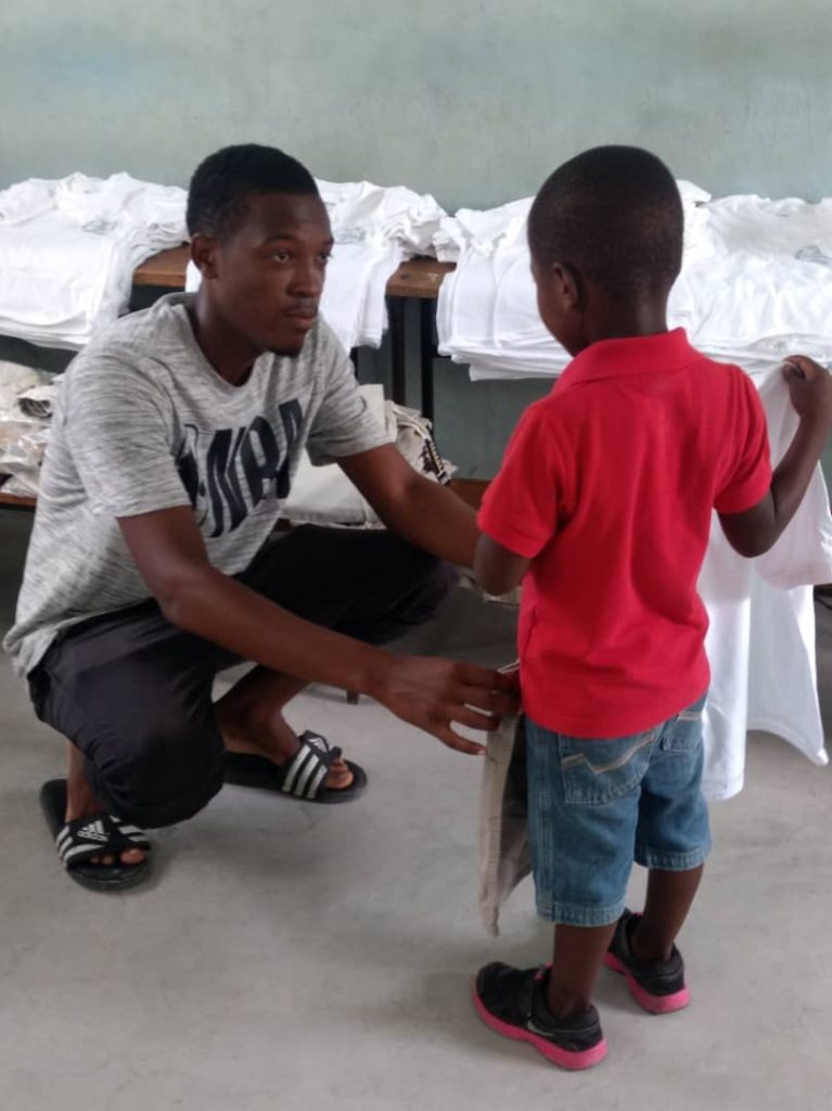 an adult man giving a shirt to a young boy