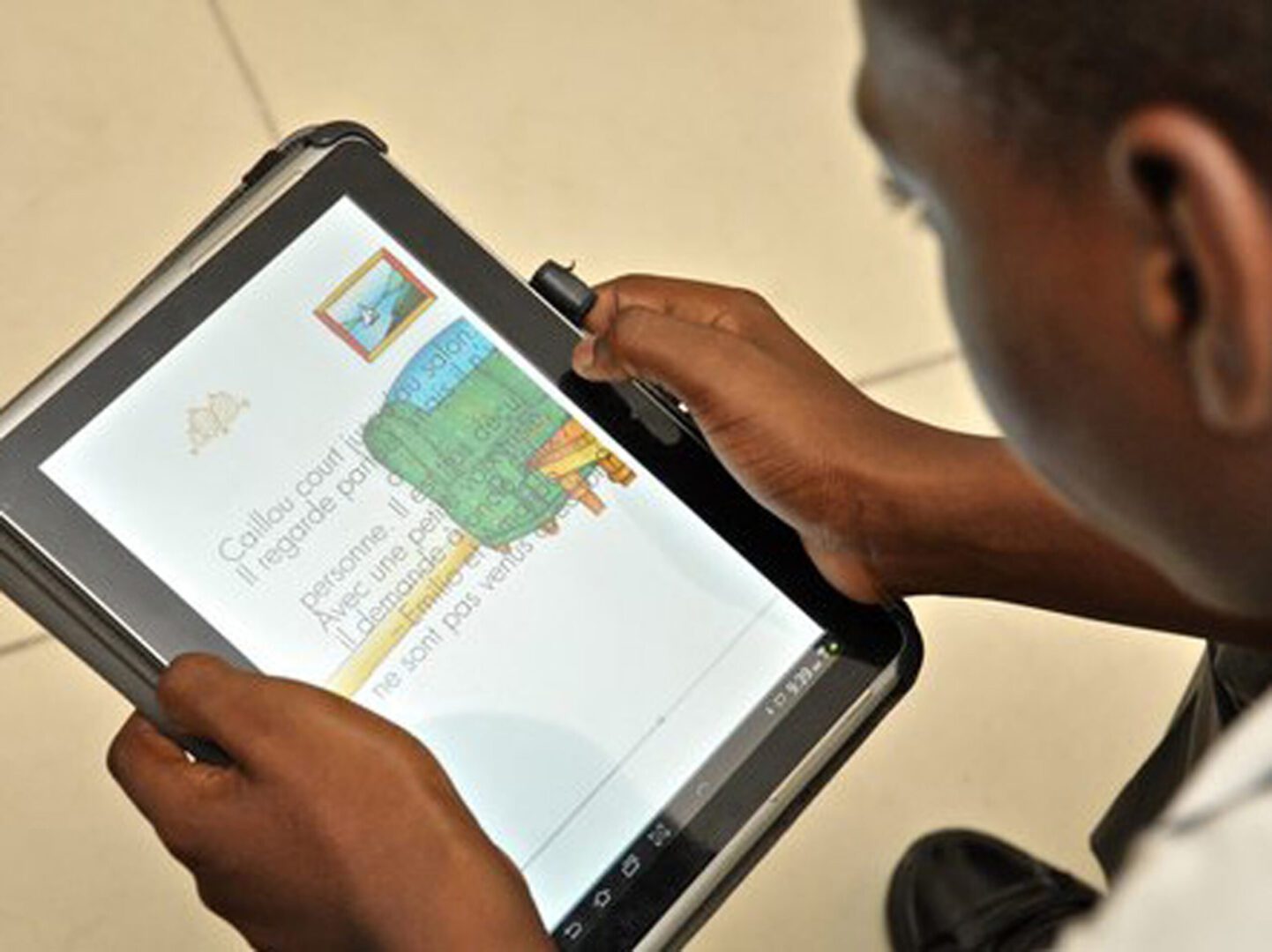 A picture of the school boy reading from the tablet