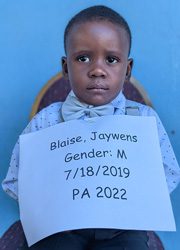 A young boy holding up a sign that says blaise jaywens gender m.