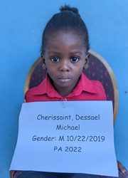 A young girl holding up a sign that says cherrisant dessain michael.