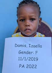 A young girl holding up a sign that says damis izella gender f 11 - 2021.