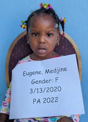 A young girl holding a sign that says eugene medine gender f.