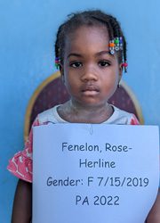 A young girl holding up a sign that says fenon rose herrine gender f 15 - 2021.