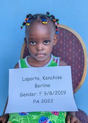 A young girl holding a sign that reads lapports kenneth bernine gender f - 8 2020.