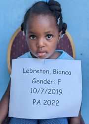 A little girl holding up a sign that says leberton bianca gender f.