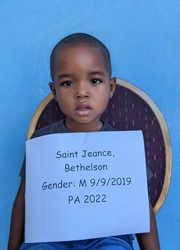 A young boy holding up a sign that says saint jean baptiston.