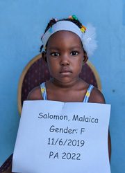 A young girl holding up a sign that says,'salomon malai gender f'.