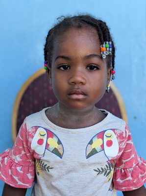 A young girl wearing pink dress looking at camera